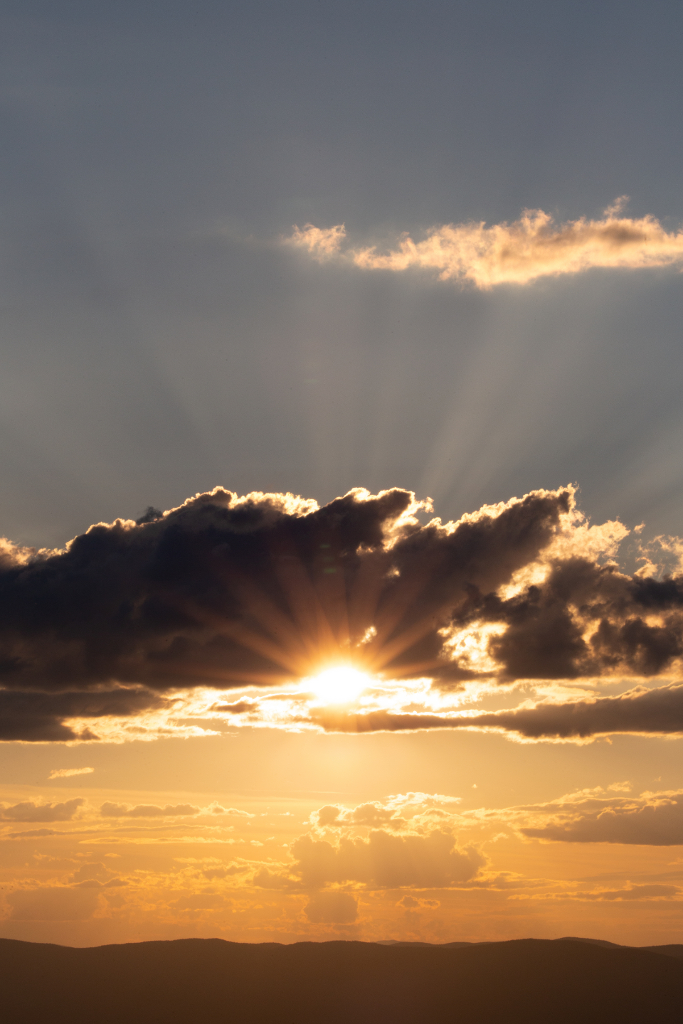 Golden sun rising through clouds, warm rays filling the sky